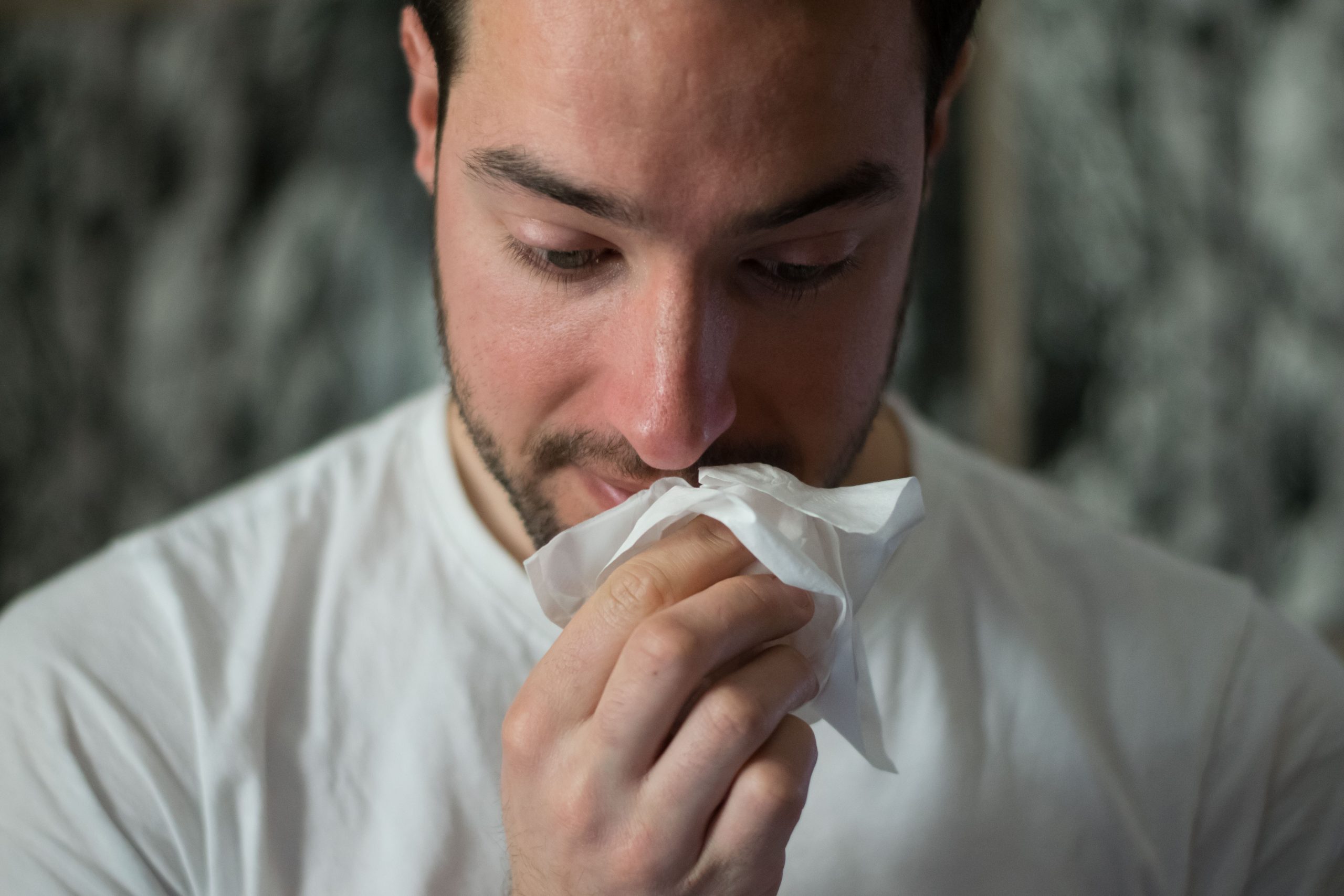 Man sneezing in a dusty home, showing the discomfort of poor air quality.