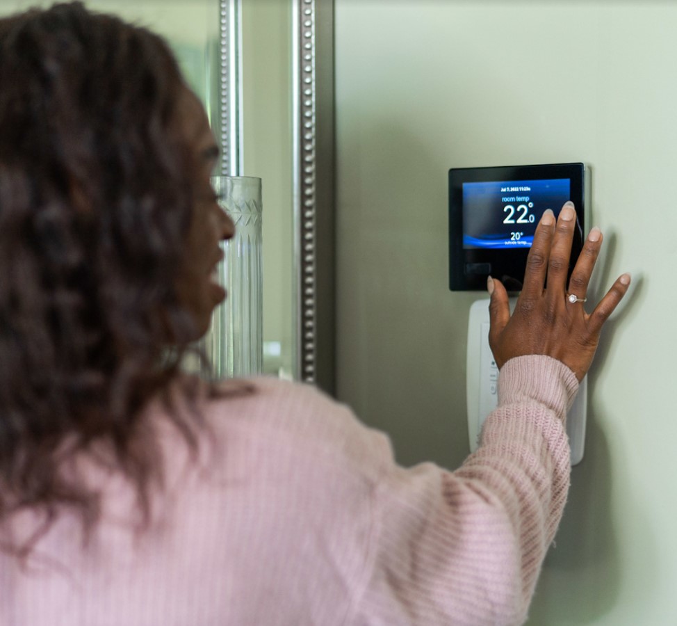 Woman checking AC thermostat settings.