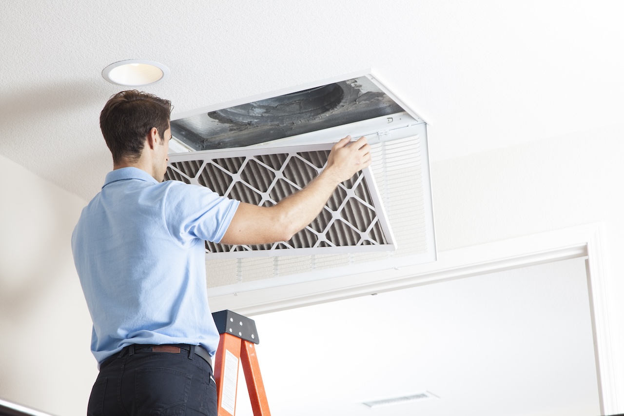 Man changing central air conditioner filter.
